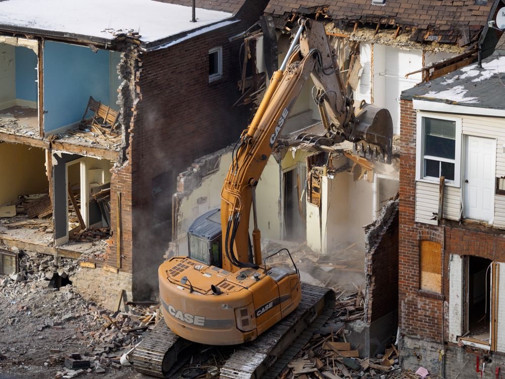 Excavator tearing down a house during a full demolition project