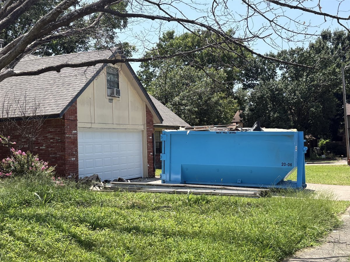 Durco Dumpsters blue roll-off dumpster parked beside a brick home