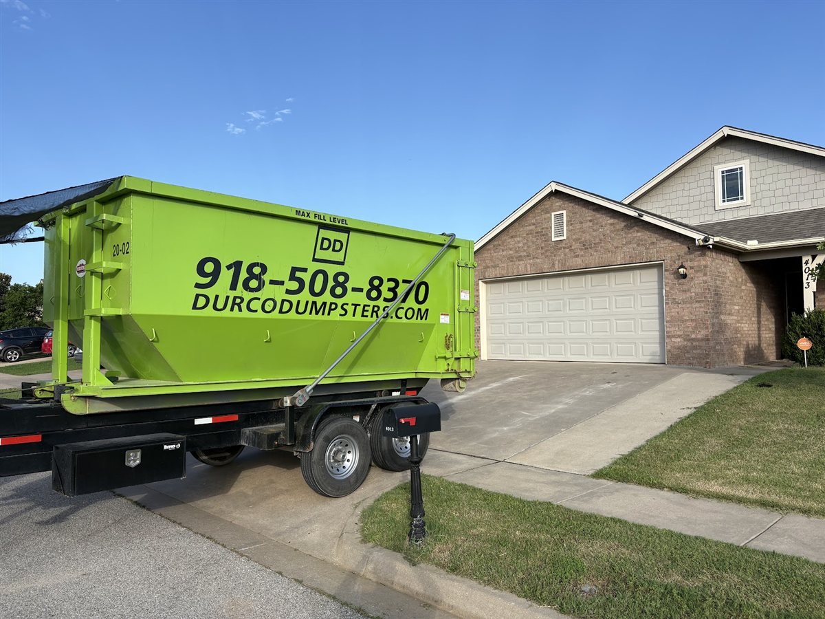 Durco Dumpsters lime green dumpster being delivered on a trailer to a home