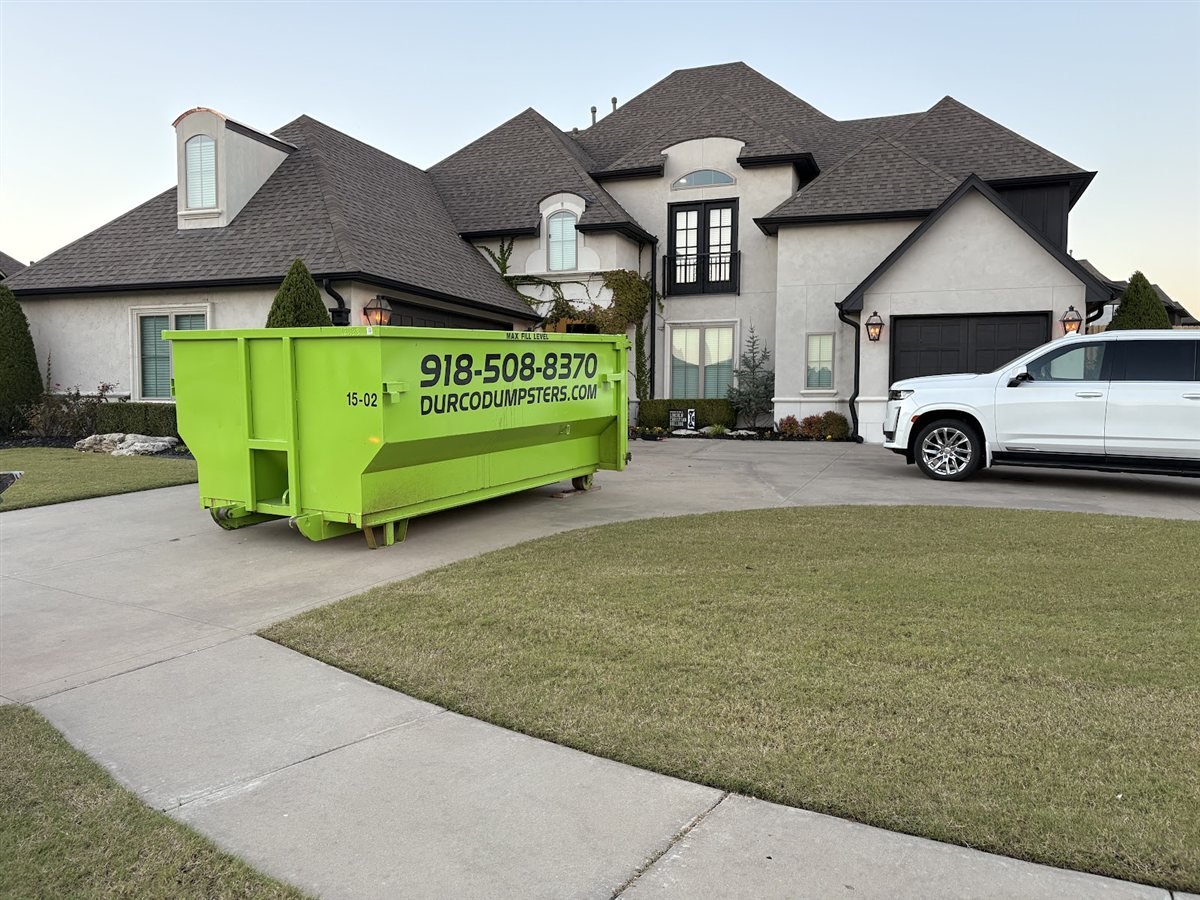 Durco Dumpsters lime green roll-off dumpster delivered to the driveway of a large home