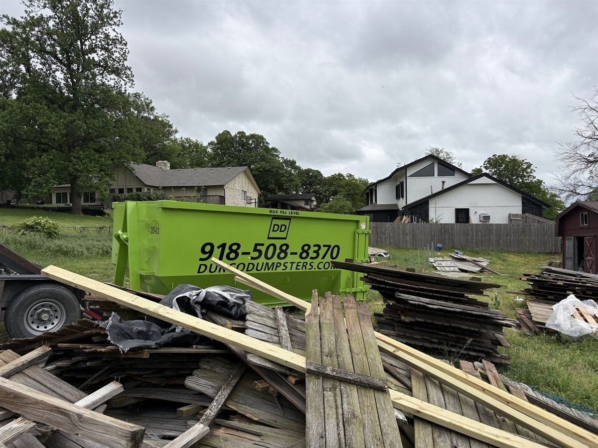 Durco Dumpsters roll-off dumpster next to a pile of lumber and demolition debris
