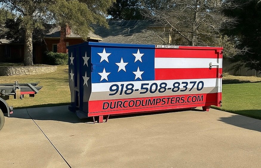 Durco Dumpsters flag-wrapped roll-off dumpster with phone number 918-508-8370 sitting in a residential driveway