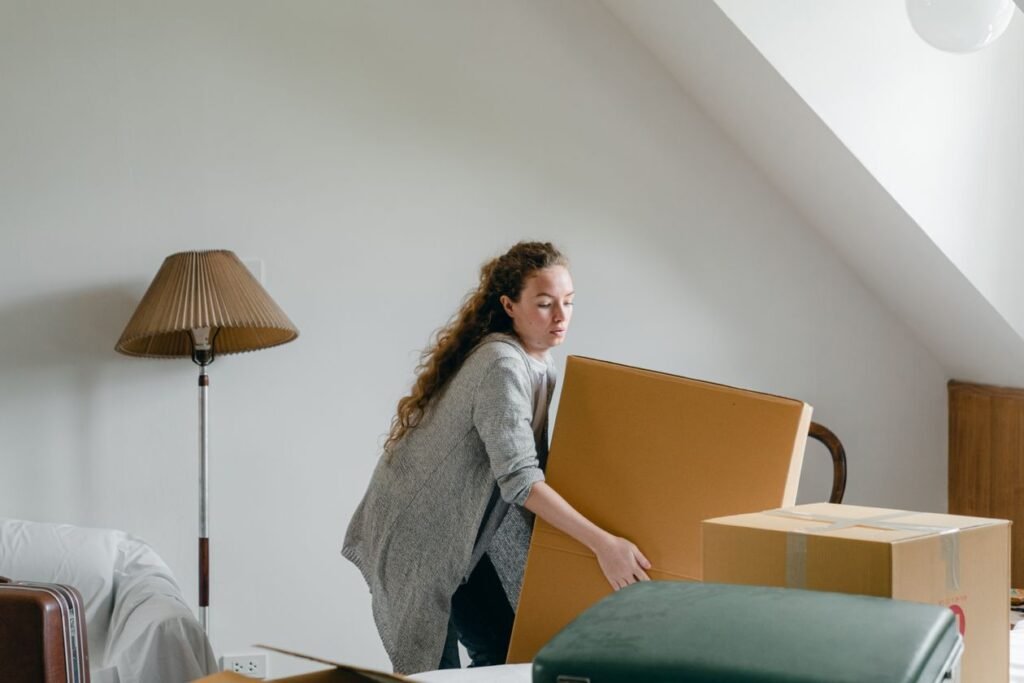 Homeowner lifting cardboard boxes while cleaning out an attic or storage room
