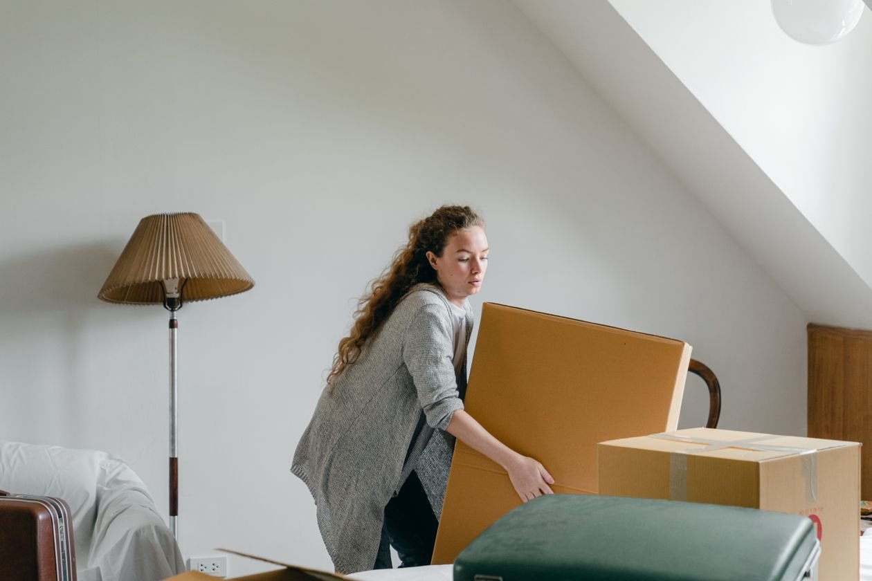 Homeowner lifting cardboard boxes while cleaning out an attic or storage room