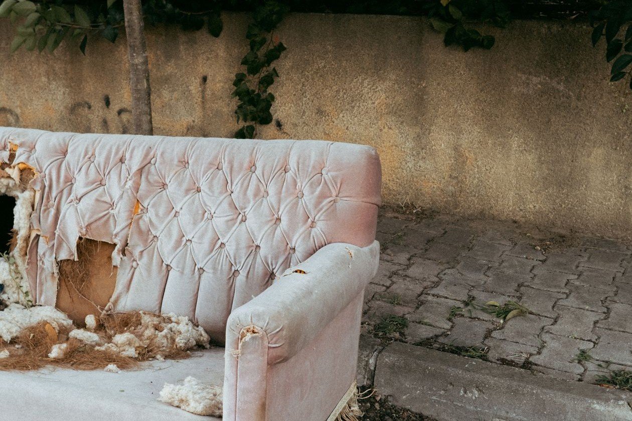 Old worn-out couch left outside waiting for bulk trash pickup
